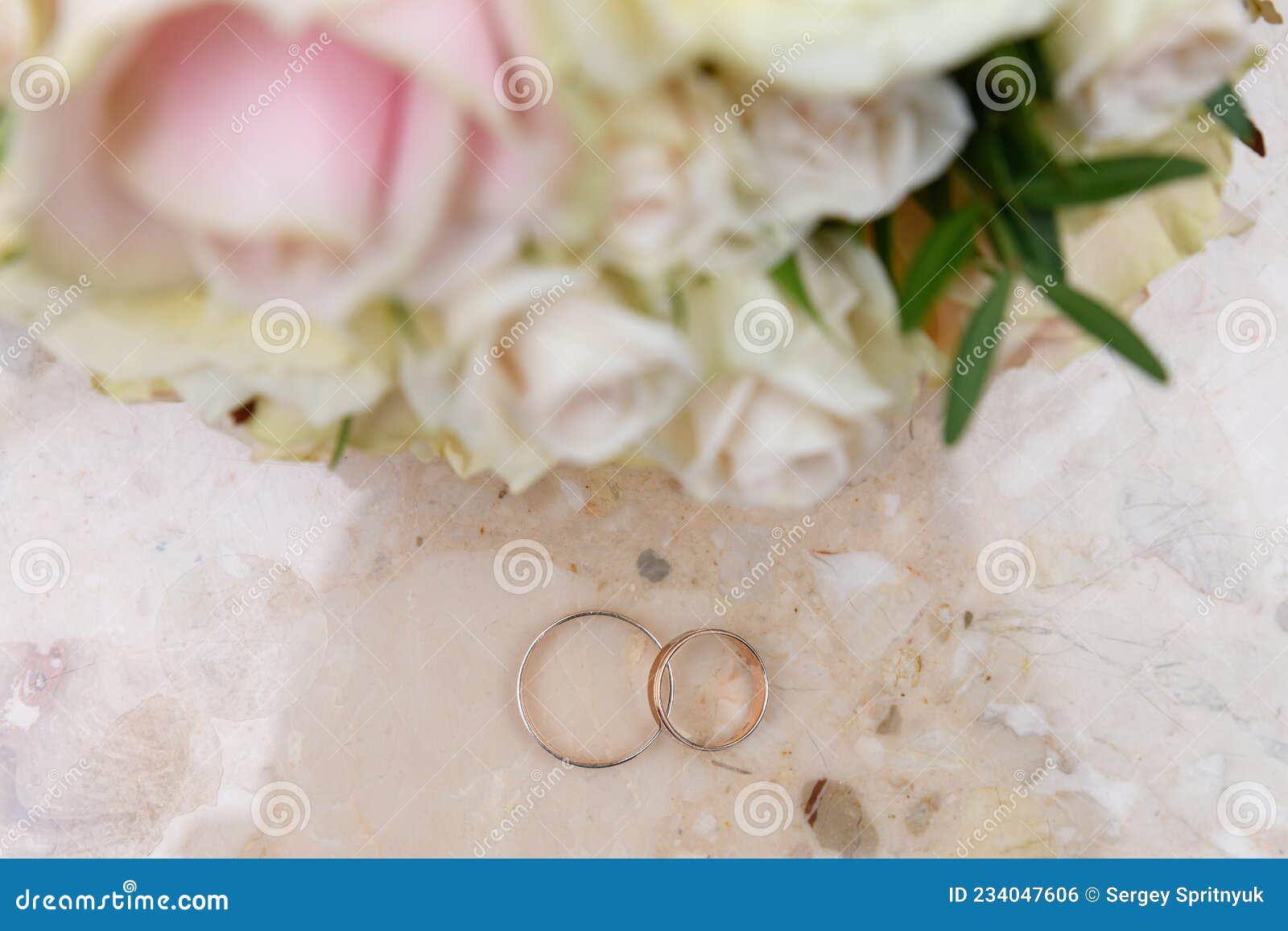 Two Gold Wedding Rings are Lying on a Stone Table Next To the Bride S ...