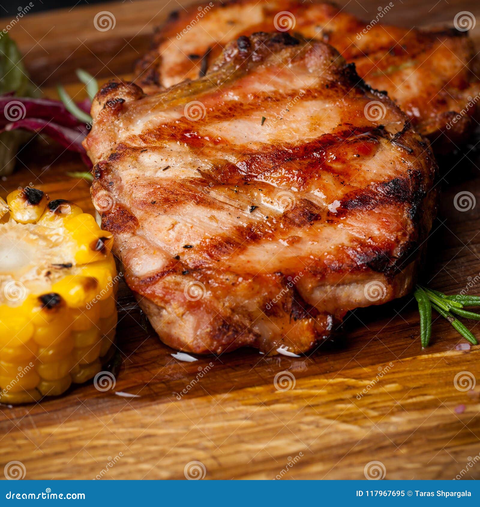 Two Grilled Steaks with Corn and Salad on a Wooden Plank Stock Image