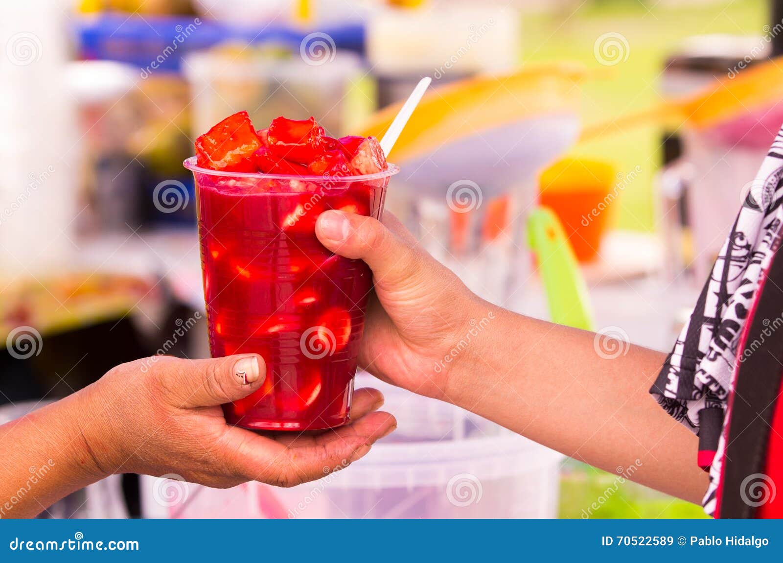 two hands holding up a glass of fruits and juice, traditional come y bebe