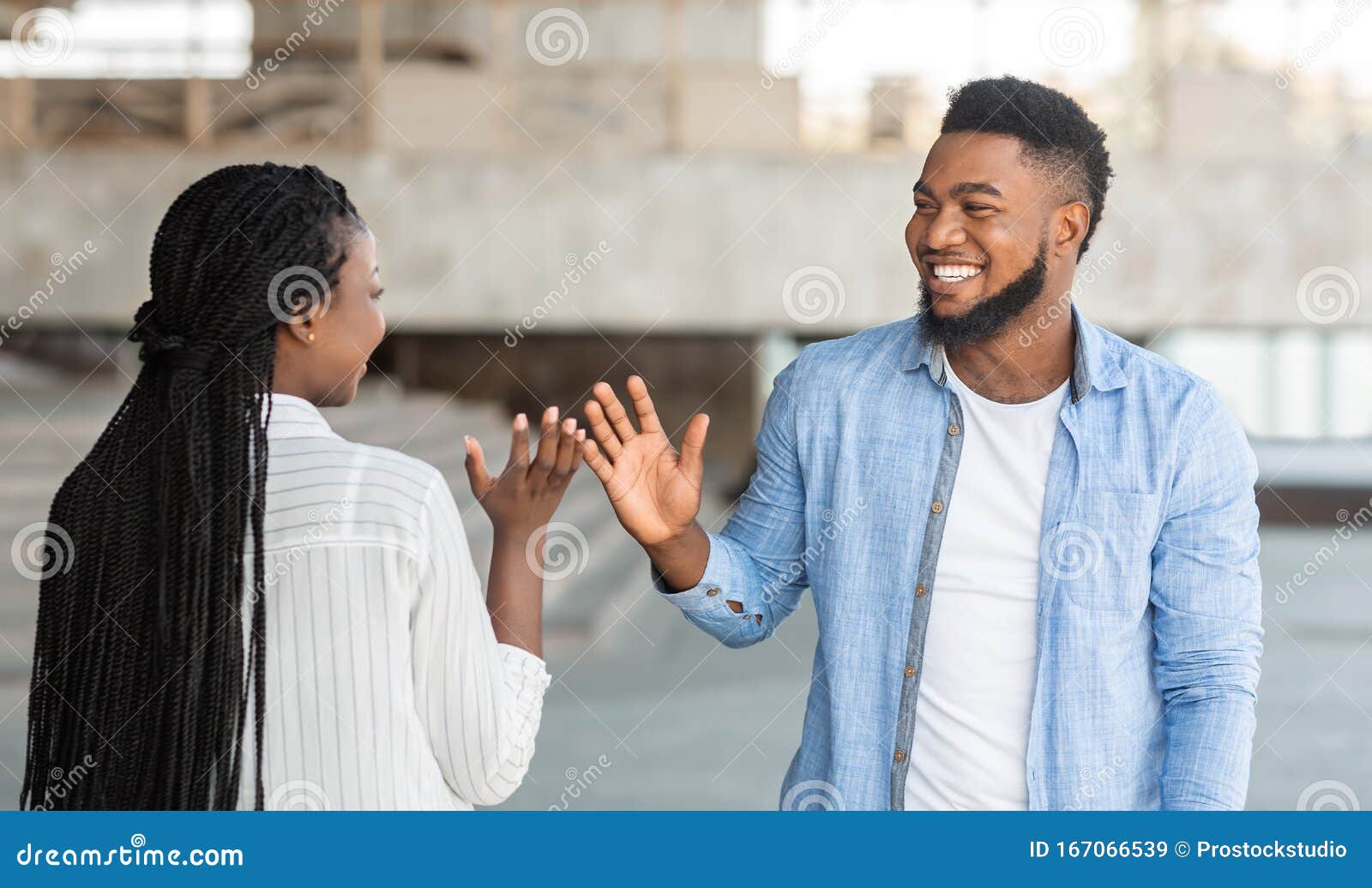 two happy african friends meeting and greeting each other on street