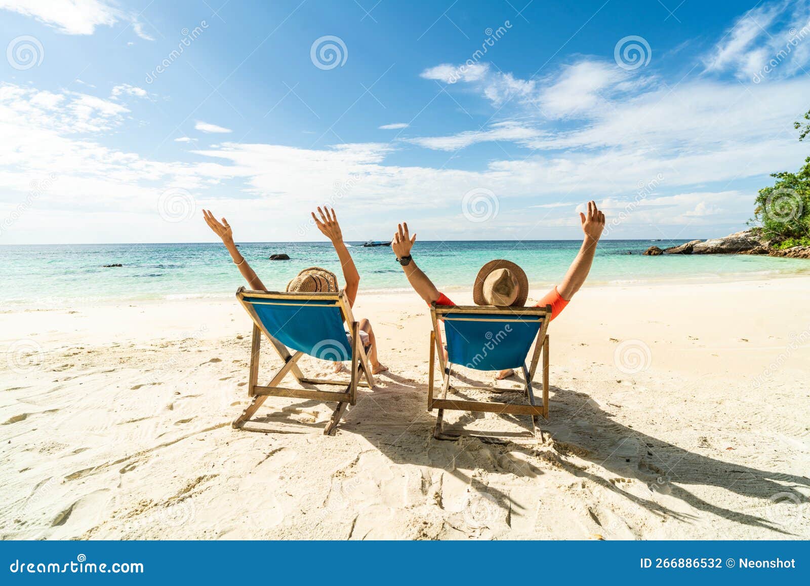 Two Happy People Having Fun On The Beach Sitting On Blue Sunbed With