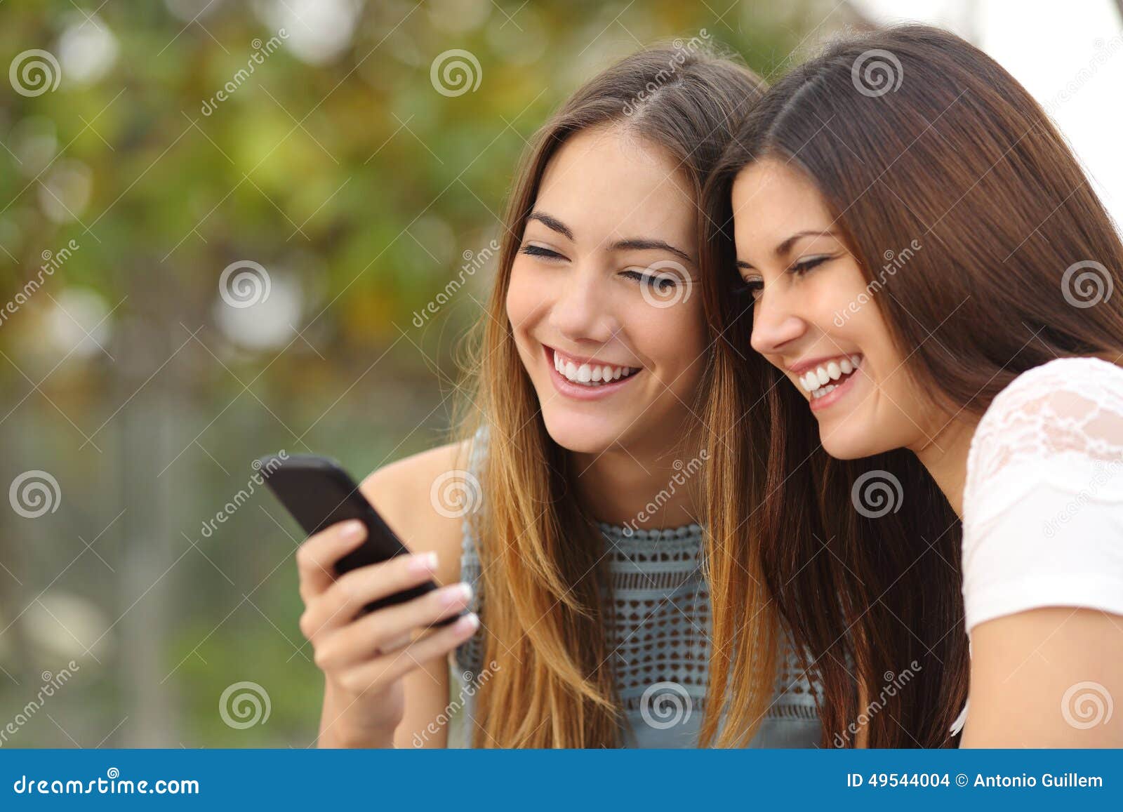 two happy women friends sharing a smart phone