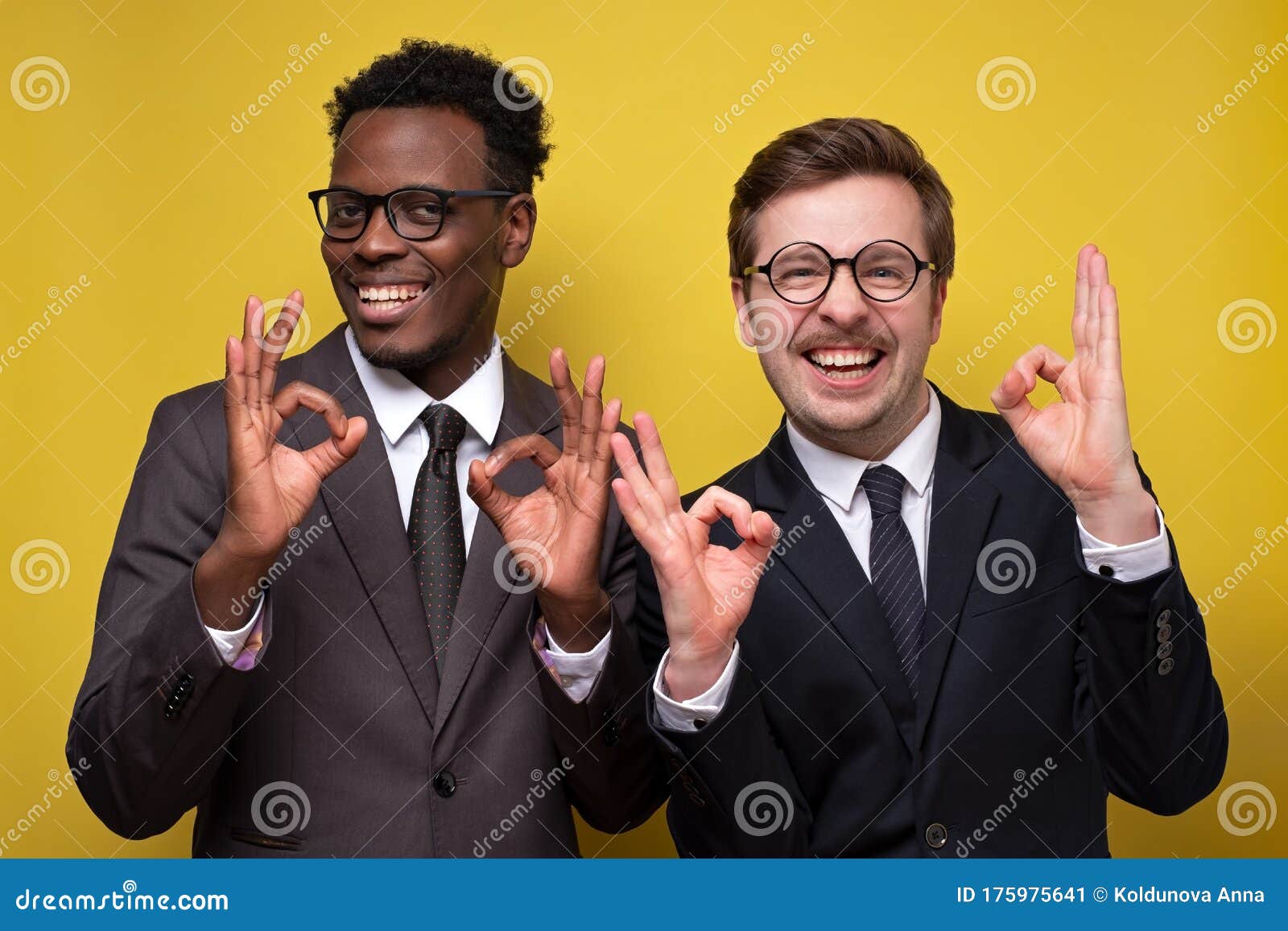 two happy young african and caucasian businessmen showing ok sign