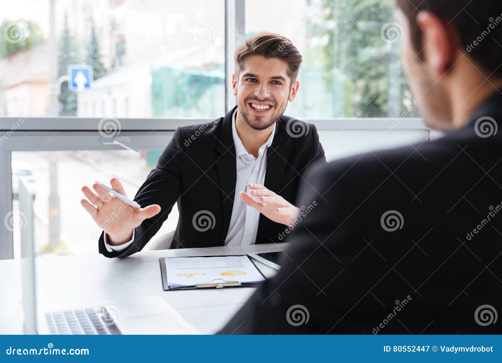 two happy young businessmen sitting and working on business meeting