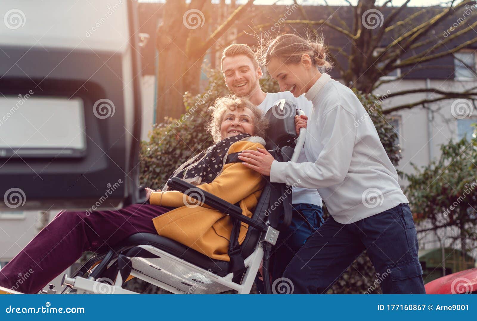 two helpers picking up disabled senior woman for transport