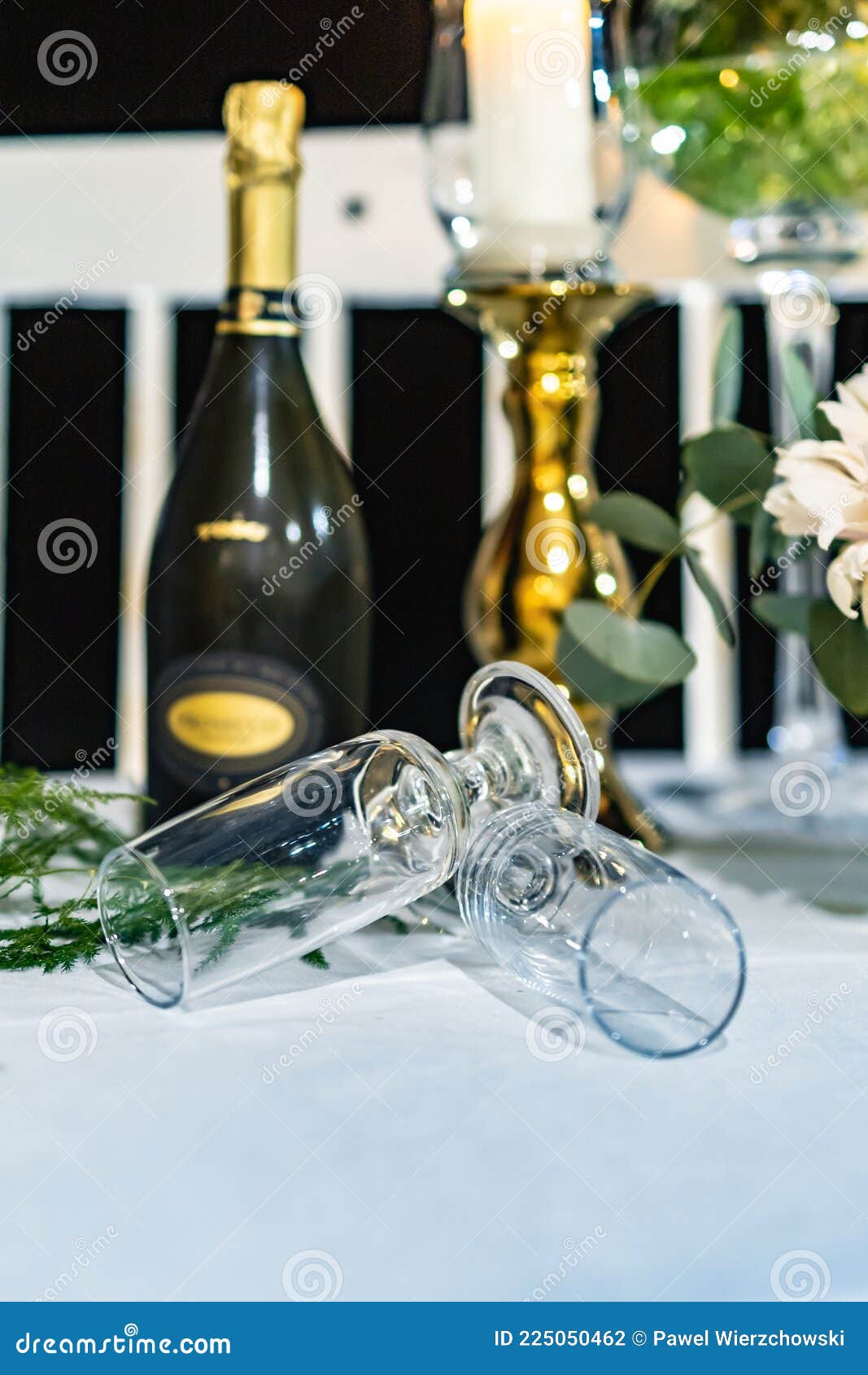 Two High Champagne Glasses Lay on Table in Front of Bottle of Champagne