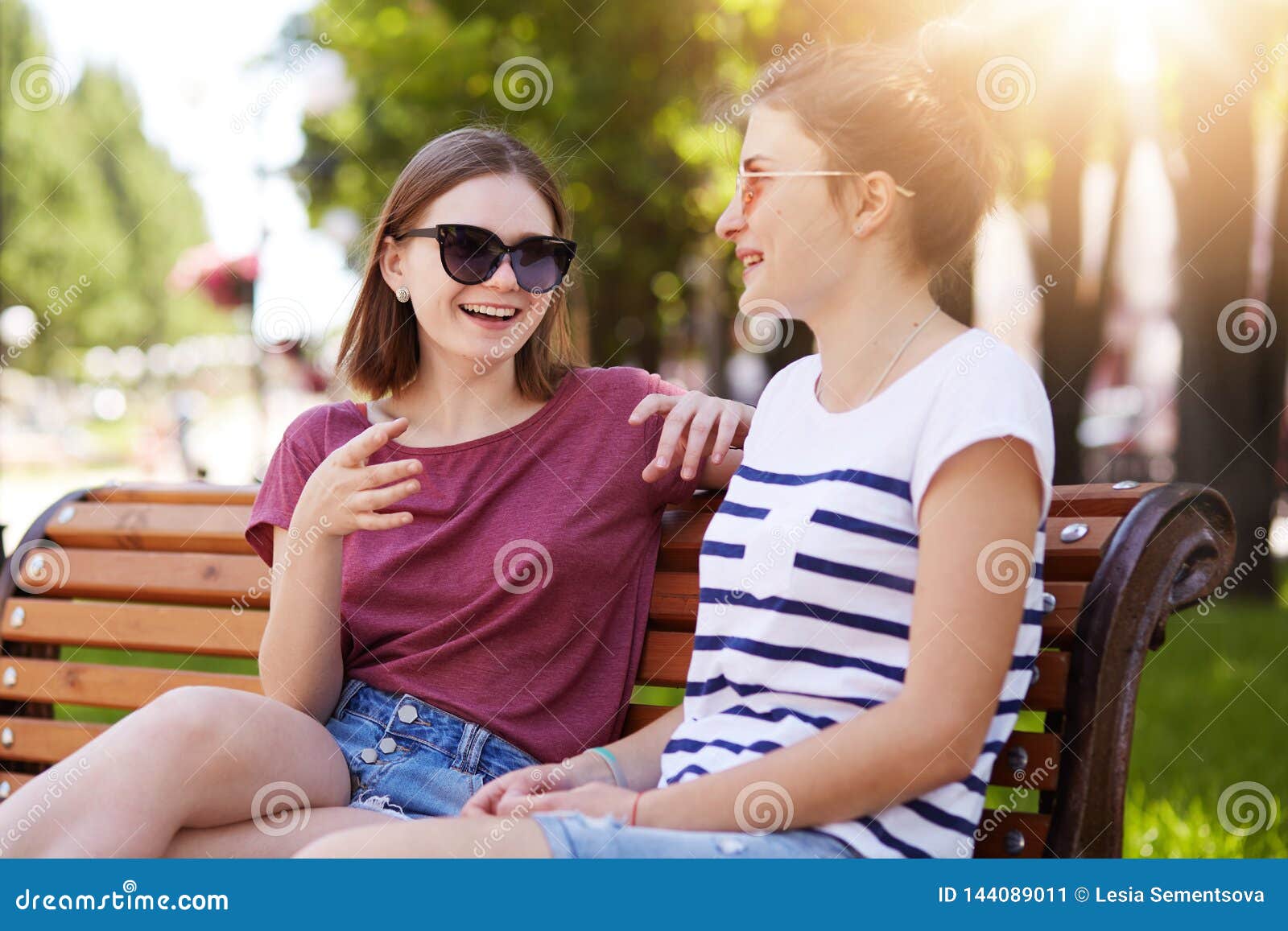 Two Joyful Girls Relax Together in Local Park Sitting on New Wooden Bench,  Make Jokes, Gossip, Remember Old Funny Moments with Stock Image - Image of  communication, enjoy: 144089011