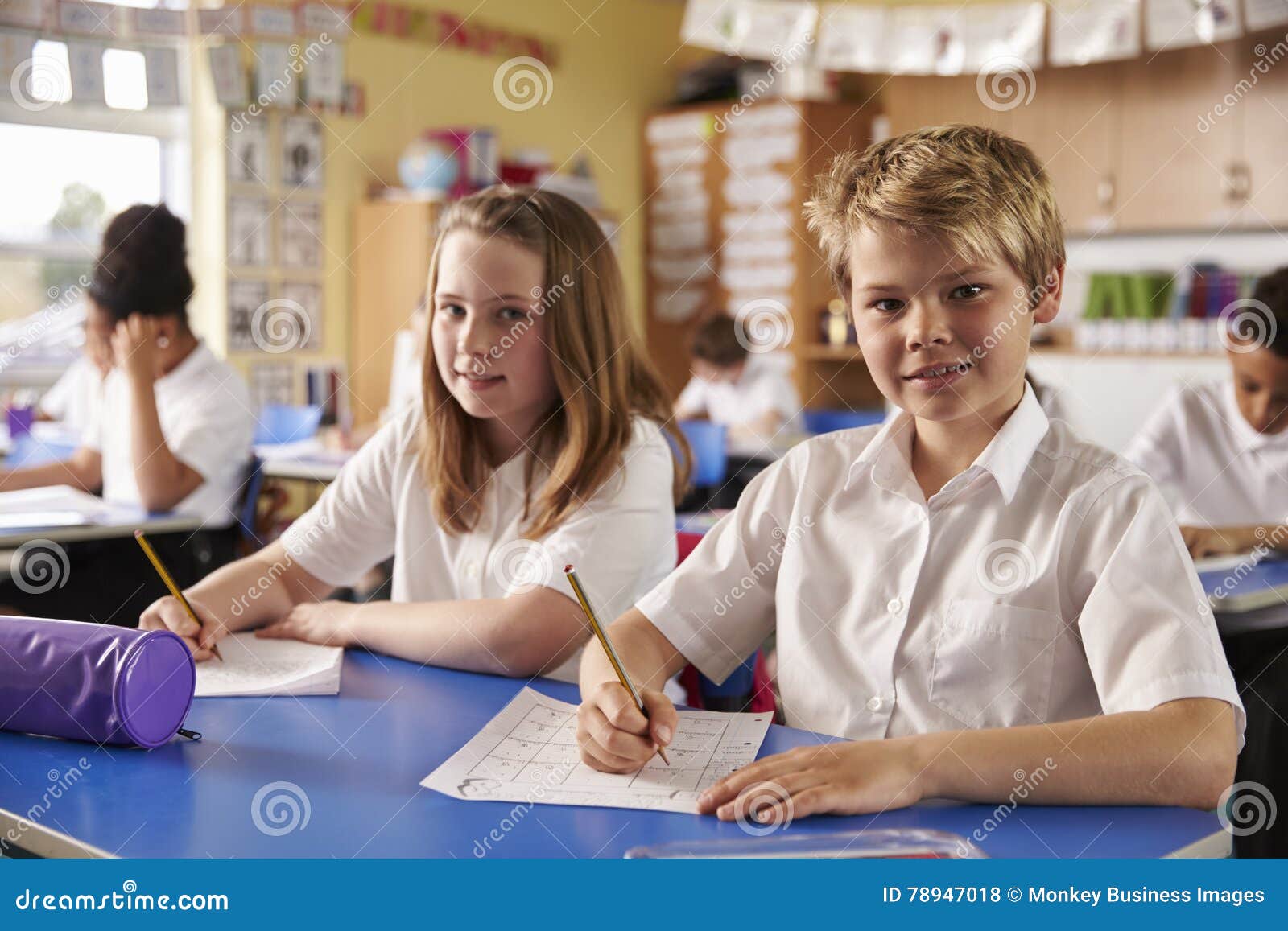 two kids in a lesson at a primary school look to camera