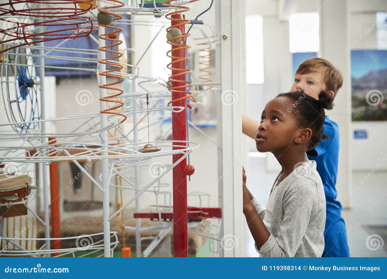 two kids looking at a science exhibit, waist up