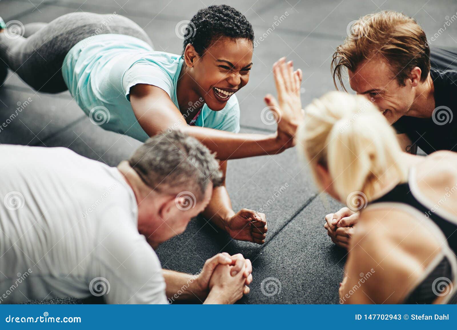 two laughing women high fiving while planking at the gym