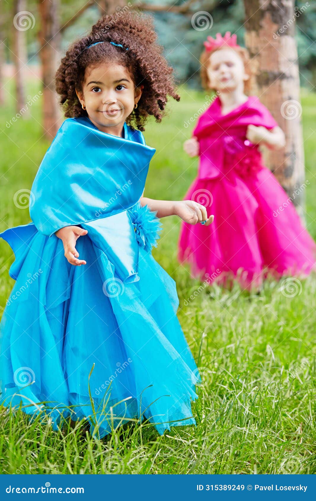two little girls in puffy gowns perform on grassy