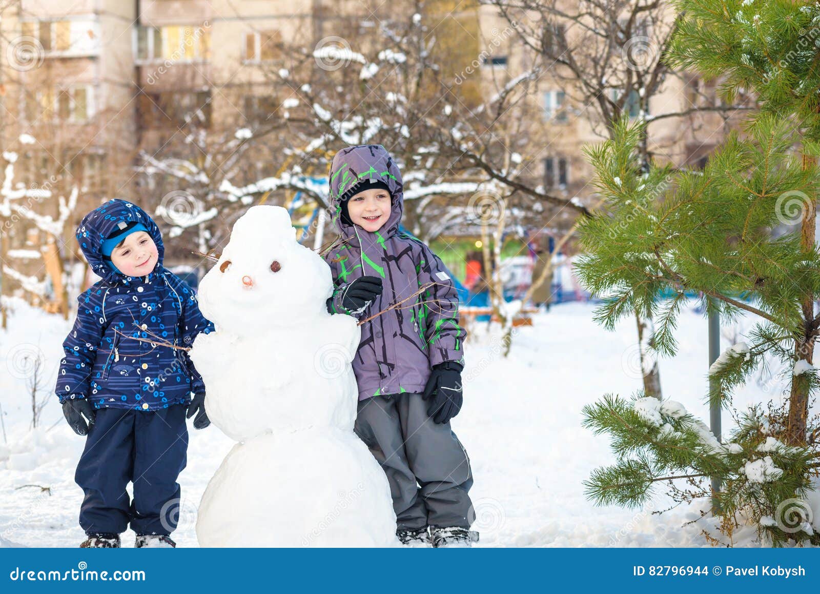 Download Two Little Siblings Kids Boys Making A Snowman, Playing And Having Fun With Snow, Outdoors On ...