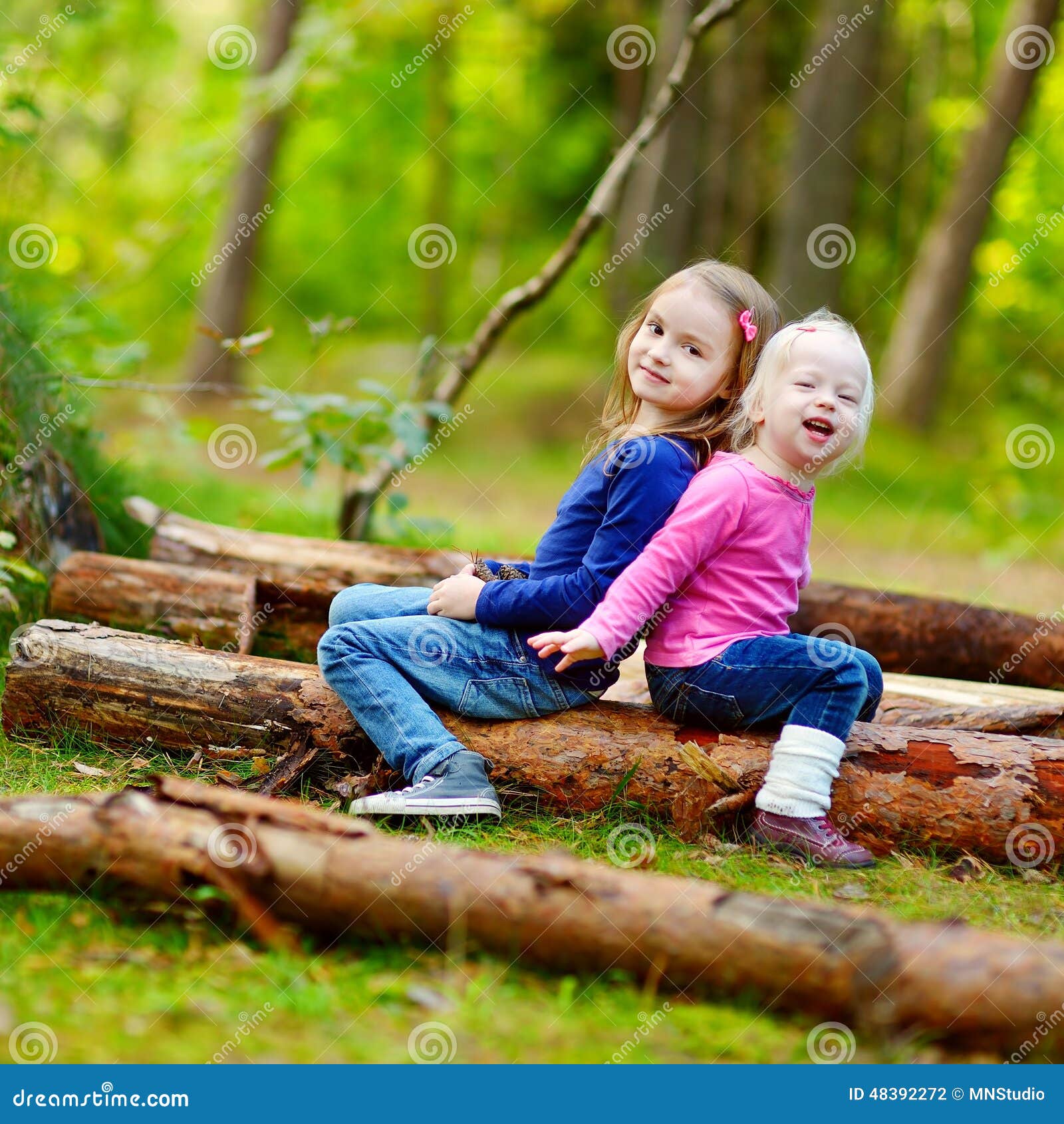 Two Little Sisters Sitting on a Log in a Forest Stock Photo - Image of ...