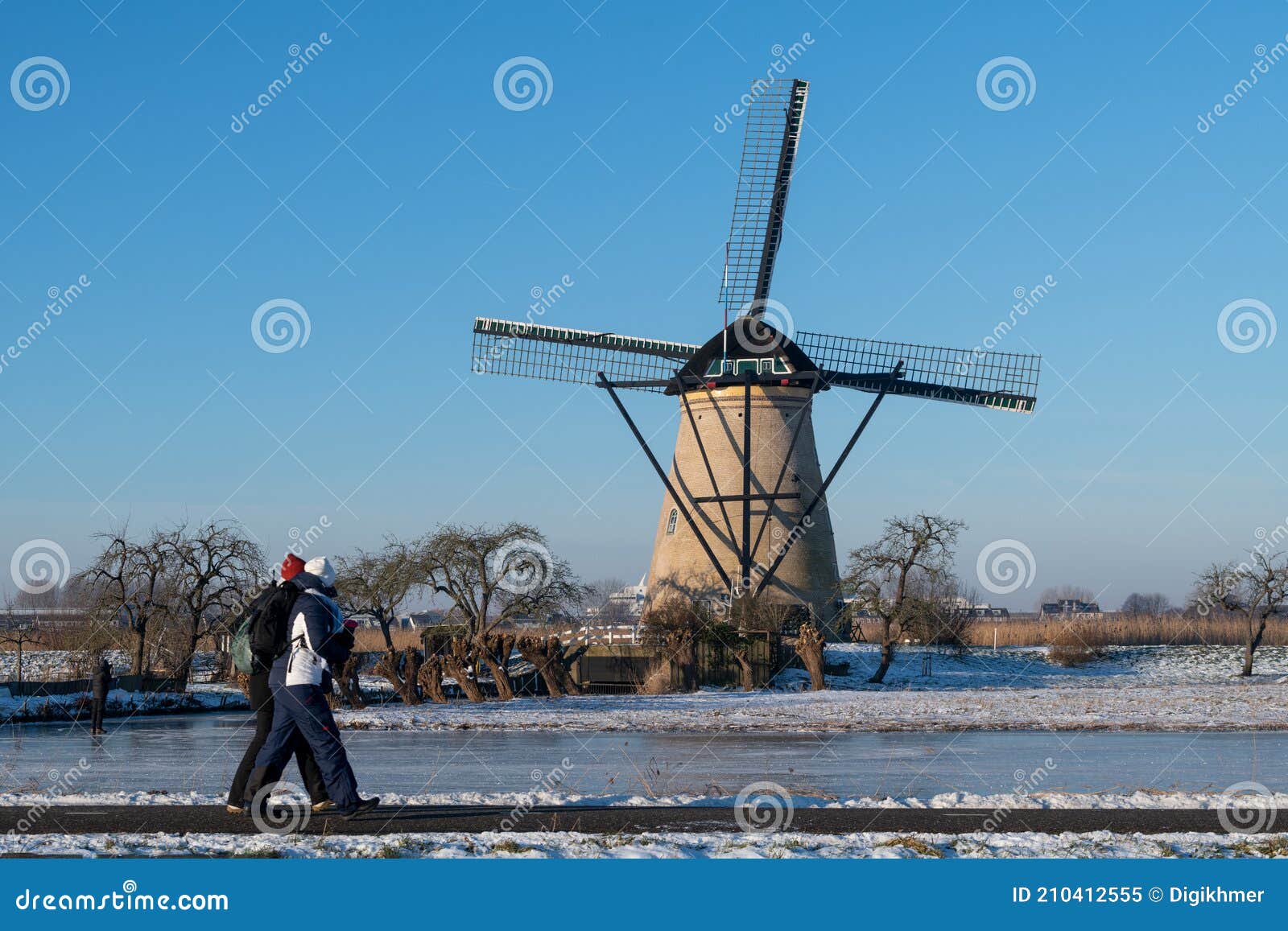 two locals on a frozen windmill canal pathway at sunrise moment