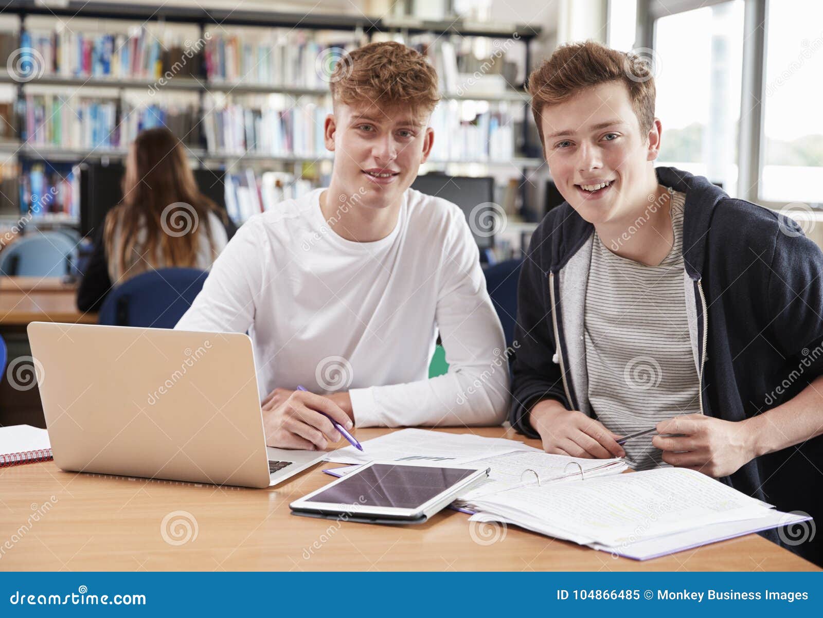 Two Male College Students Collaborating On Project In Library Stock