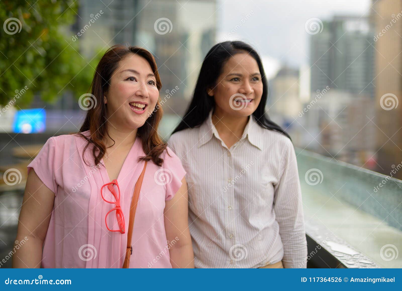 two mature asian women together against view city portrait two mature asian women together against view city 117364526