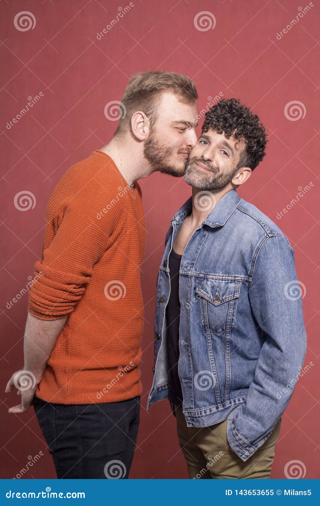 Two men, gay couple intimate. kiss on cheek. one is looking to camera, smil...