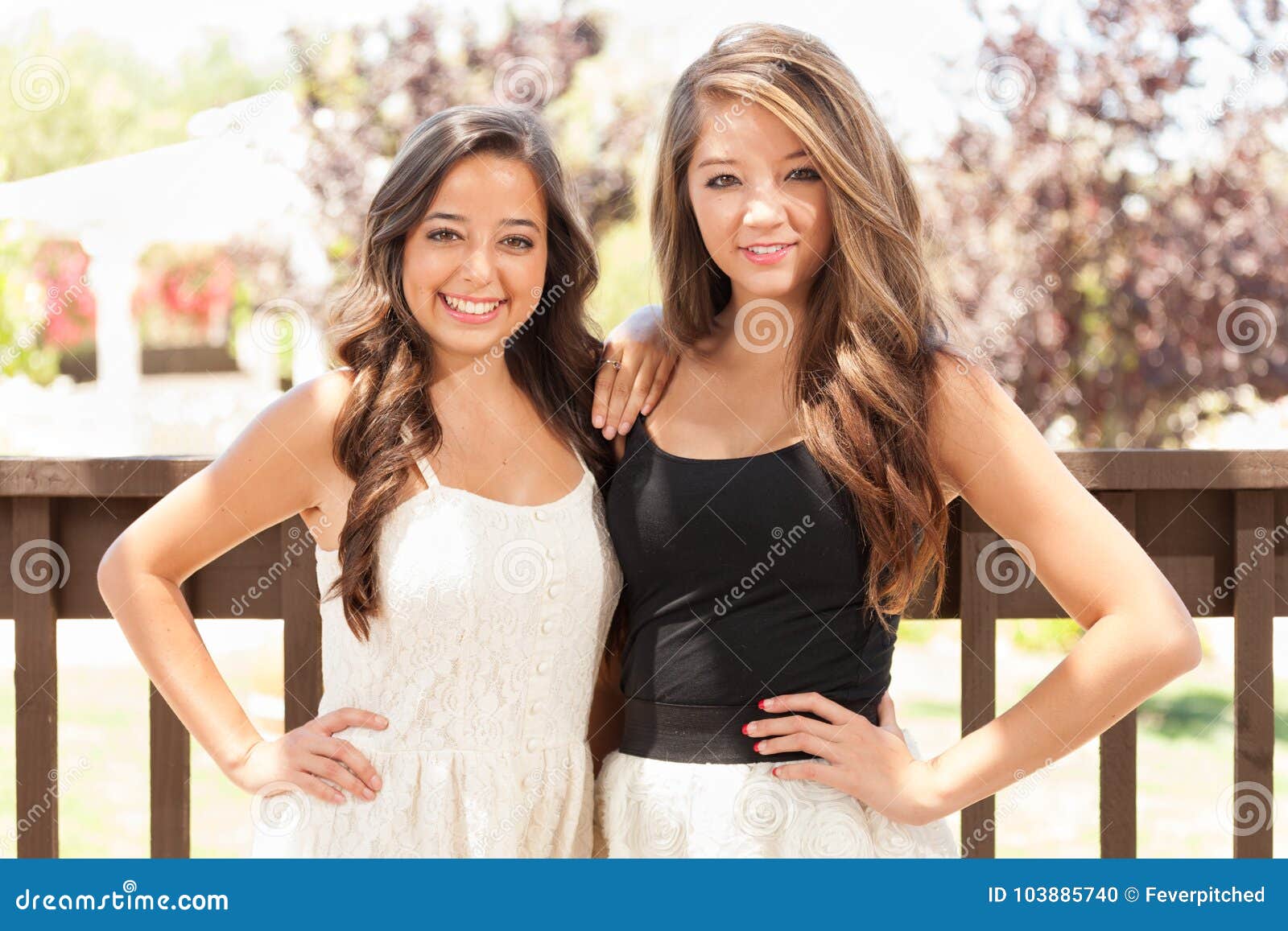 two mixed race teen girlfriends pose for portrait outdoors
