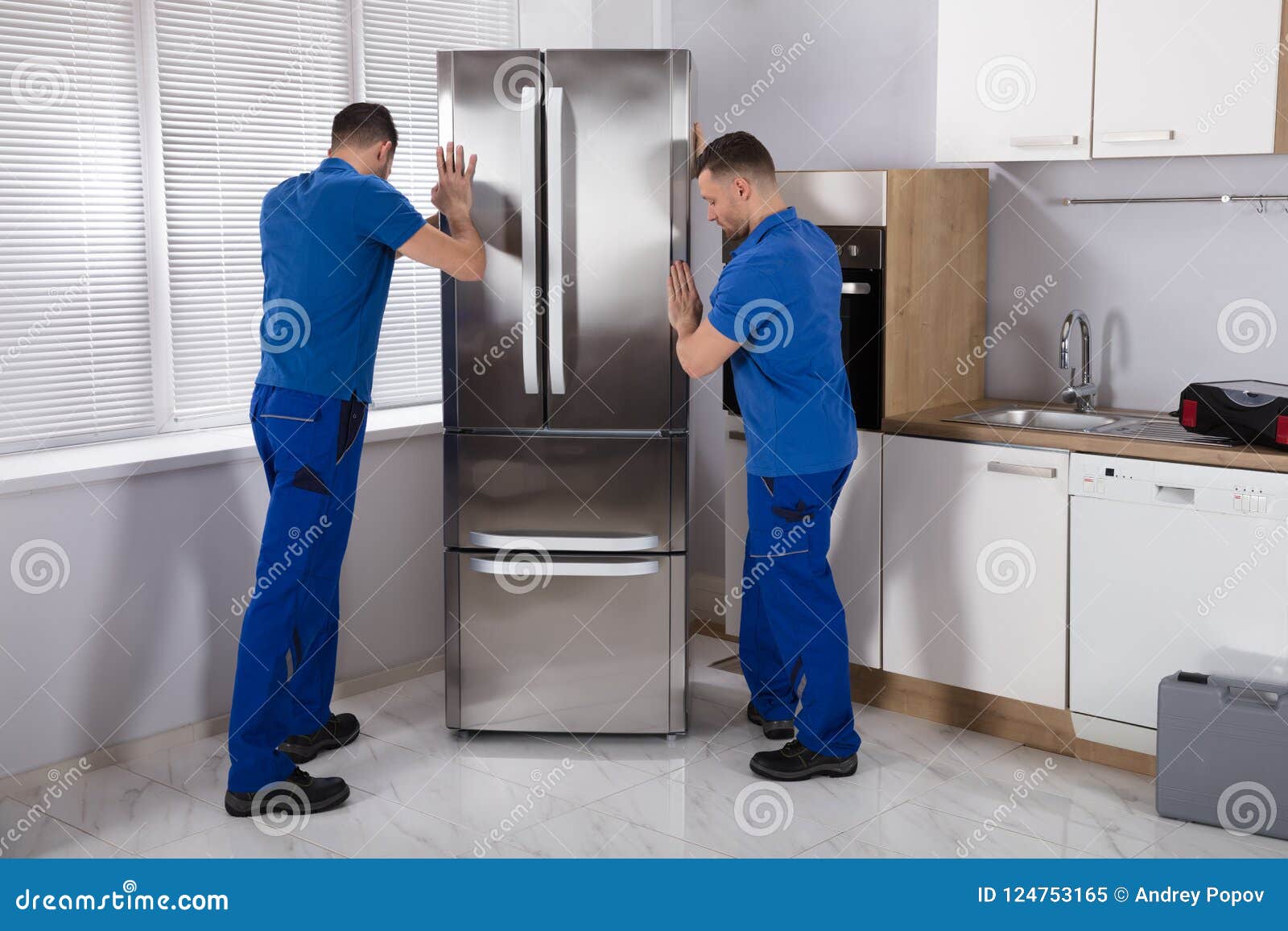 two movers placing refrigerator in kitchen