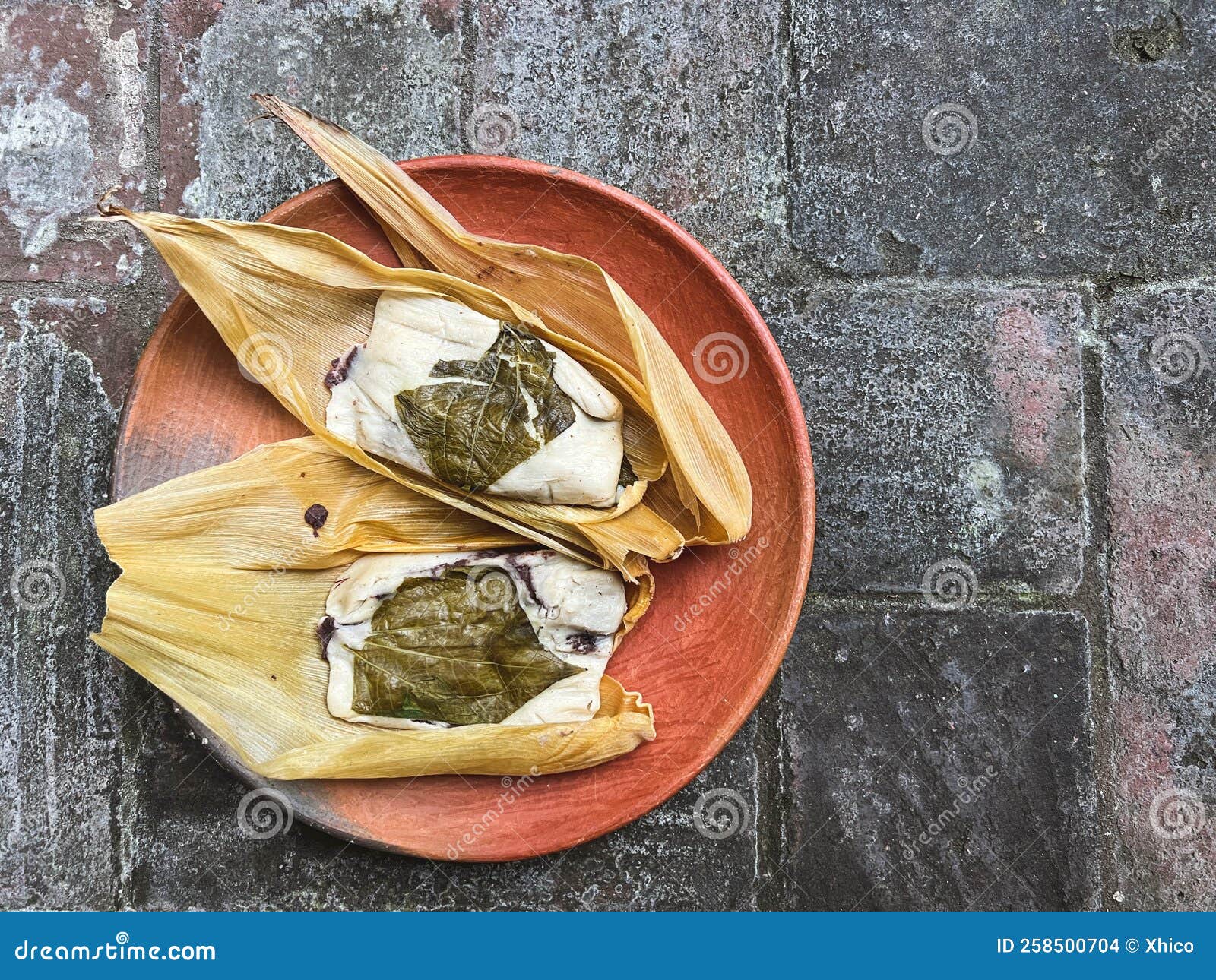 two oaxacan tamales with hoja santa wrapped on the outside of the masa