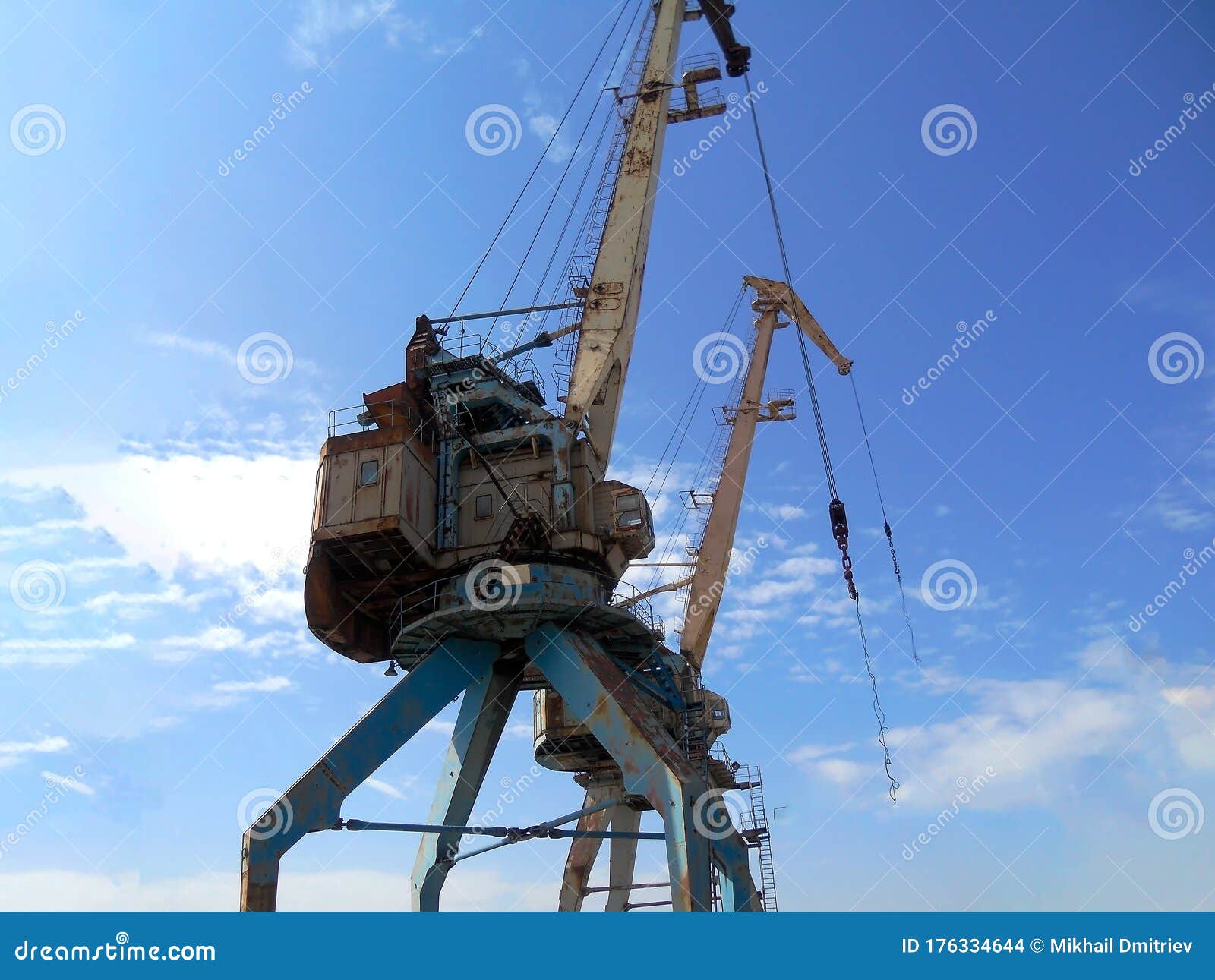 Two Old Cranes with Swinging Freight Cables in the Wind Stock Photo