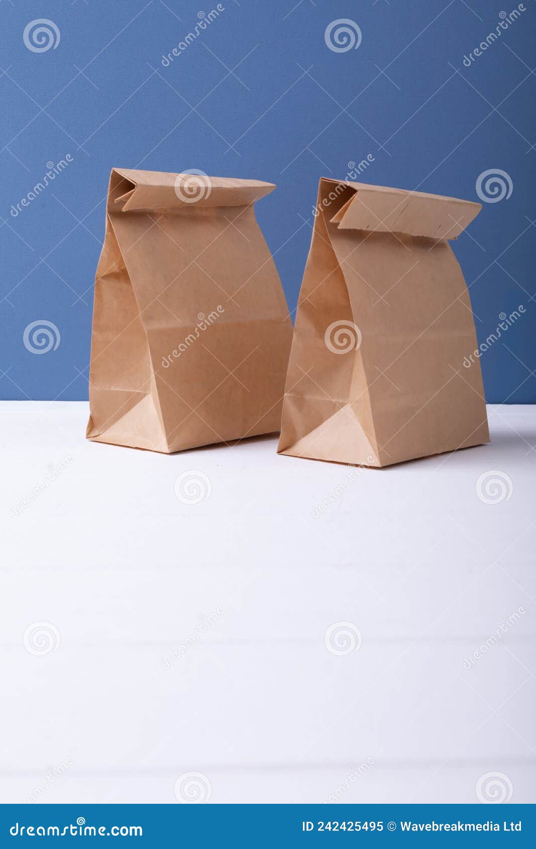 Two Paper Lunch Bags on White Surface with Copy Space on Blue