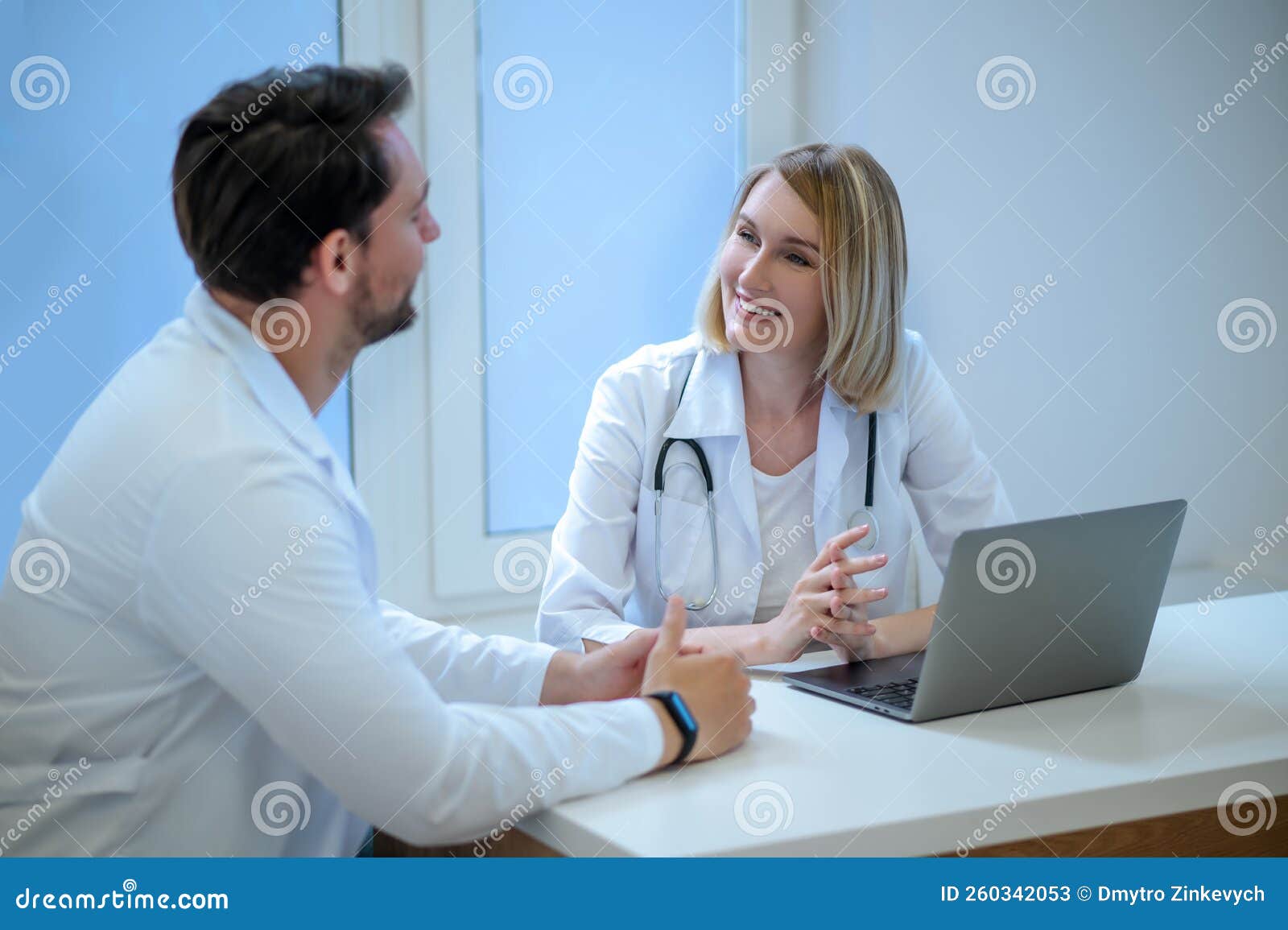 two people in lab coats discussing something and looking interested