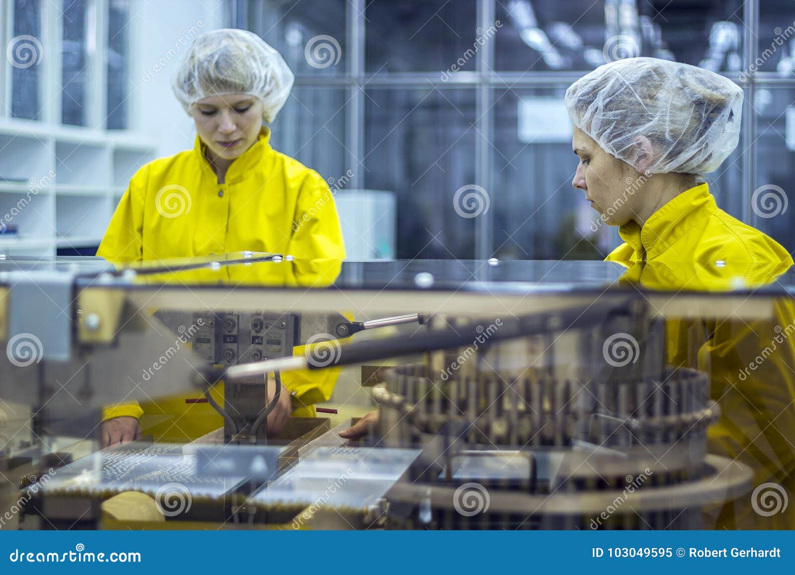 two pharmaceutical factory workers wearing protective work wear