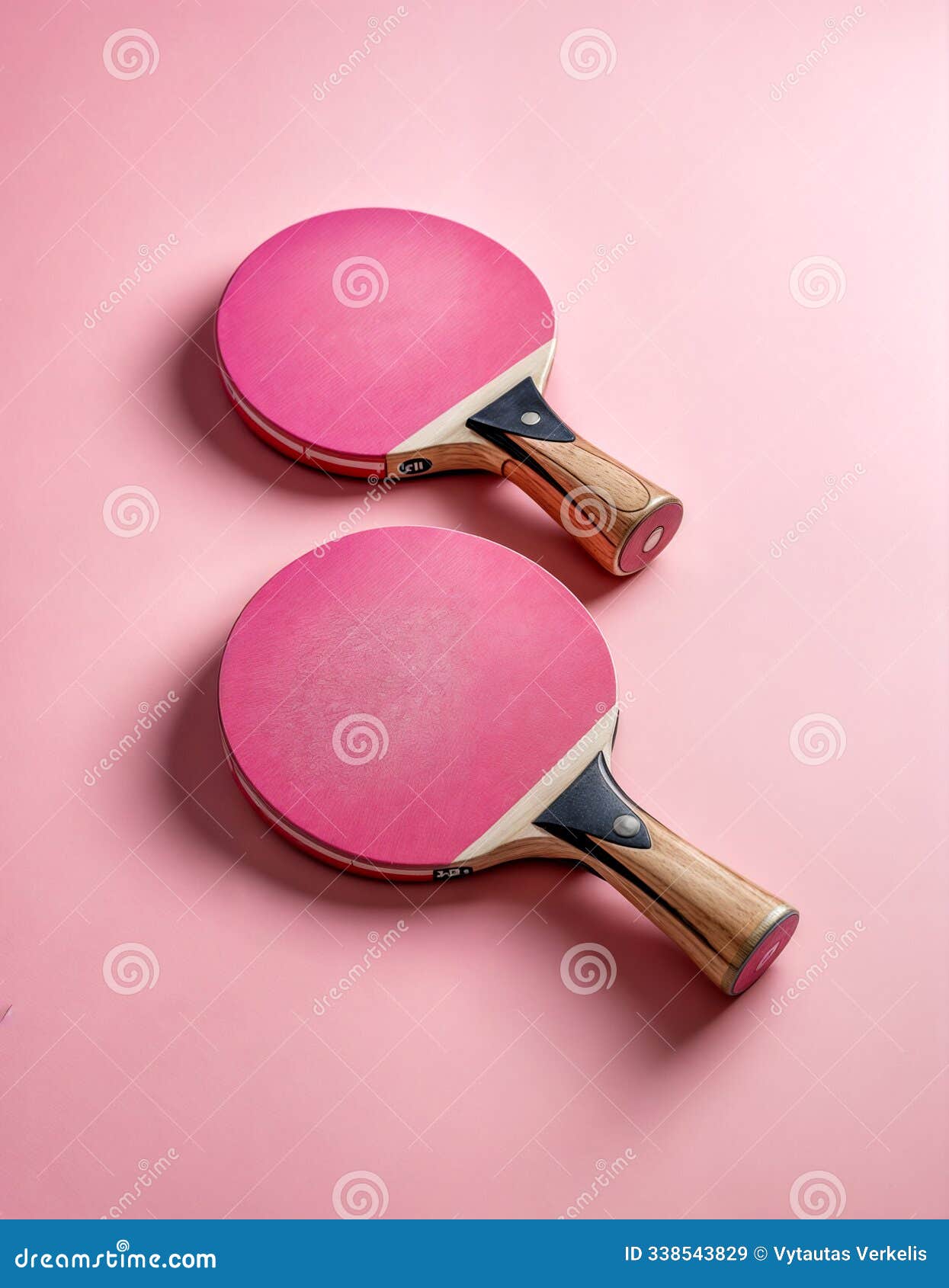 two ping pong paddles resting on pink surface