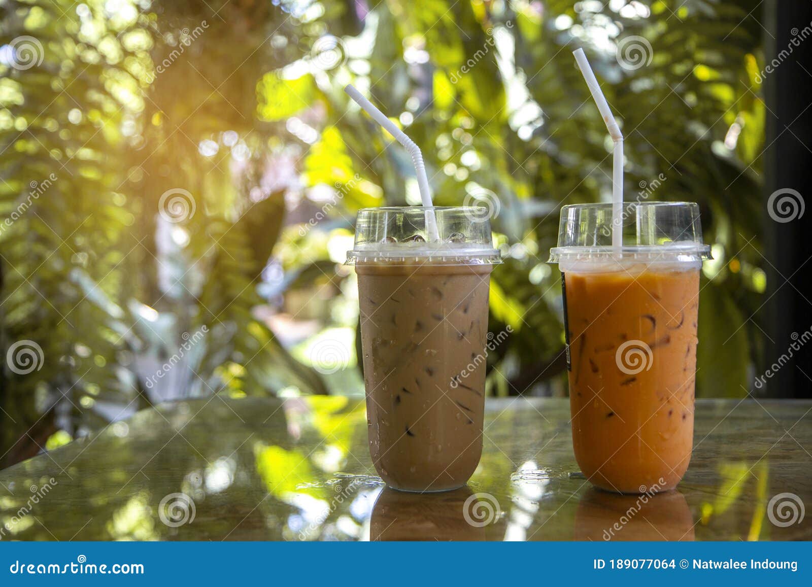 iced latte with straw in plastic cup on wood table in coffee shop