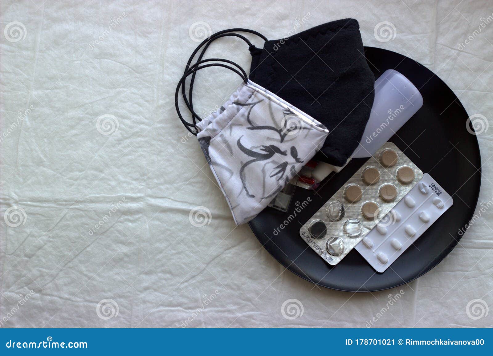 two protective face masks lie on a disposable diaper next to a plate with antipyretic and antiviral tablets