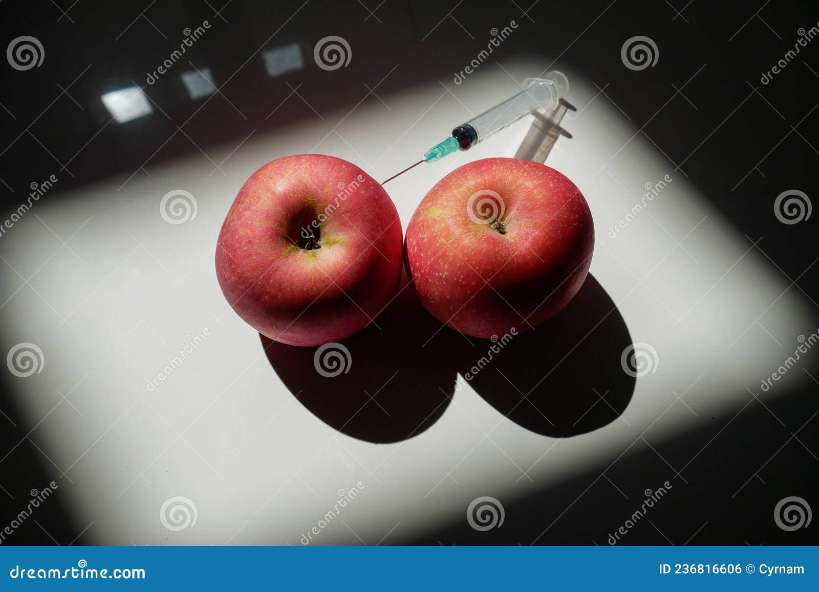 two red apples that can ize two full breasts or two muscular testicles in which is planted a syringe