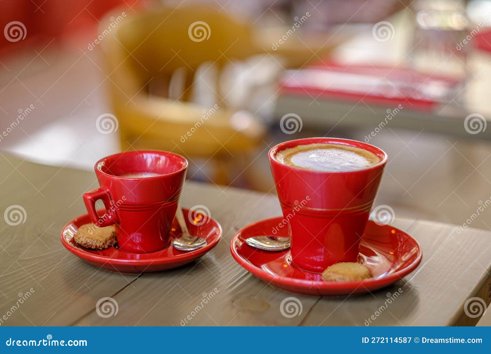 two red cups of coffee with a biscuit.