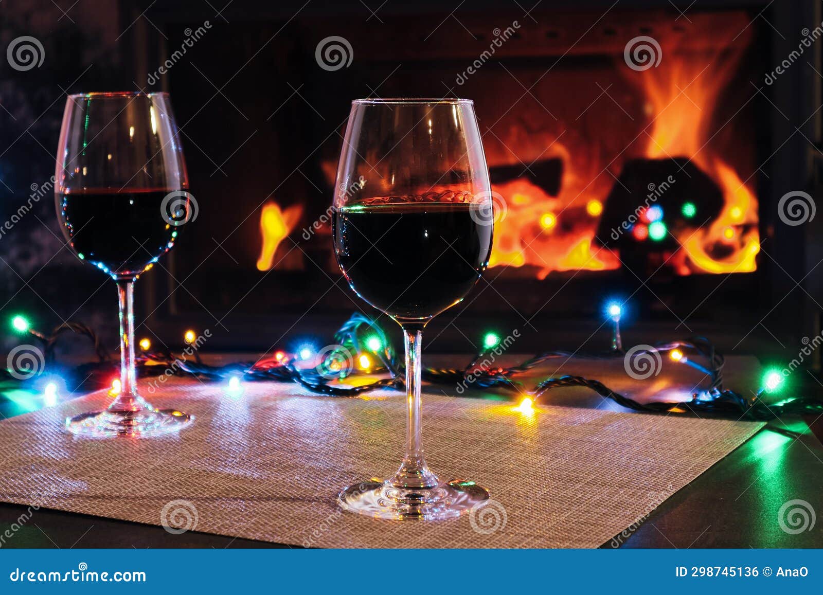 Two Red Wine Glasses and Lights Decoration on Burning Fireplace