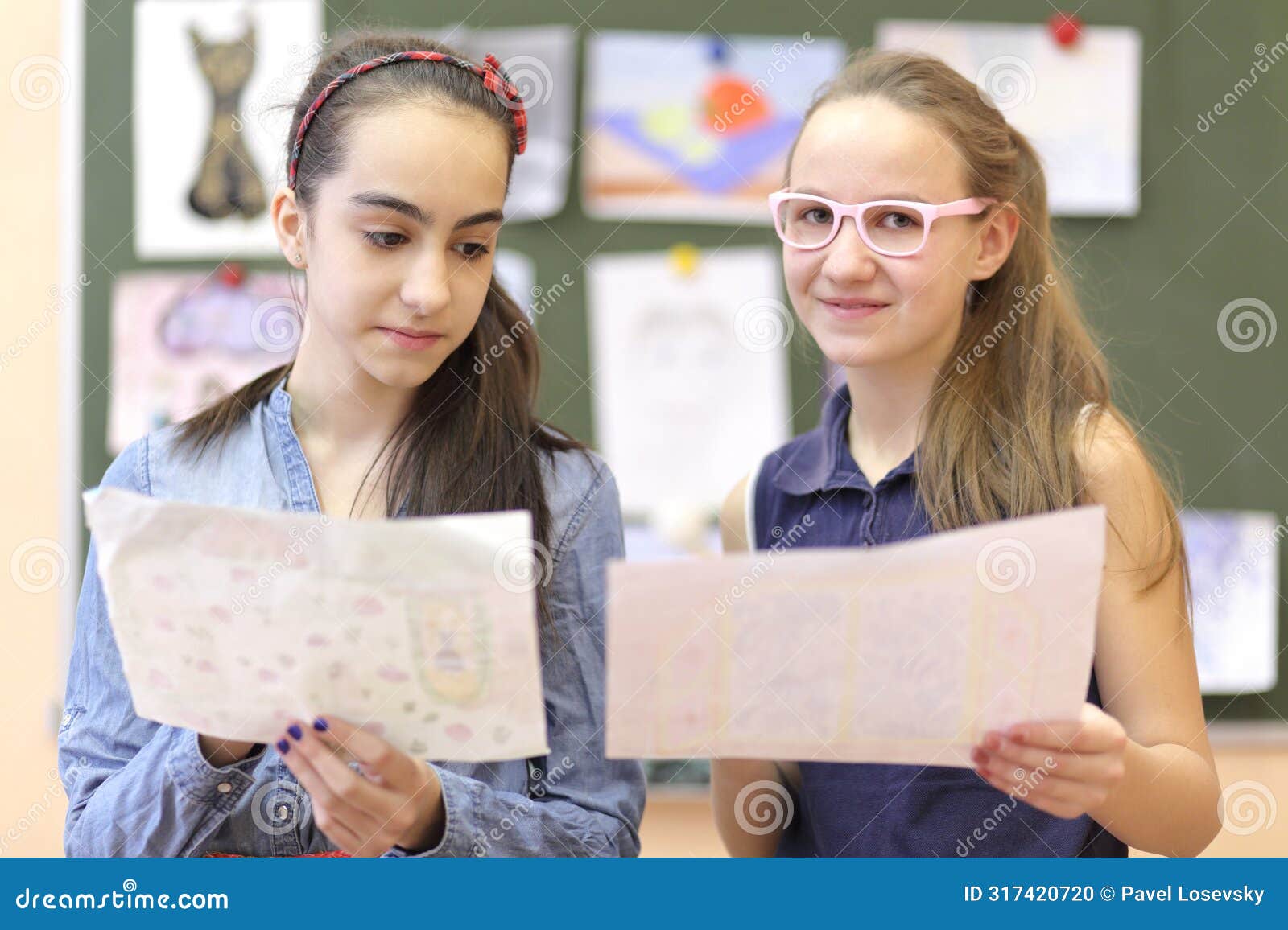 two schoolgirls consider drawings on drawing