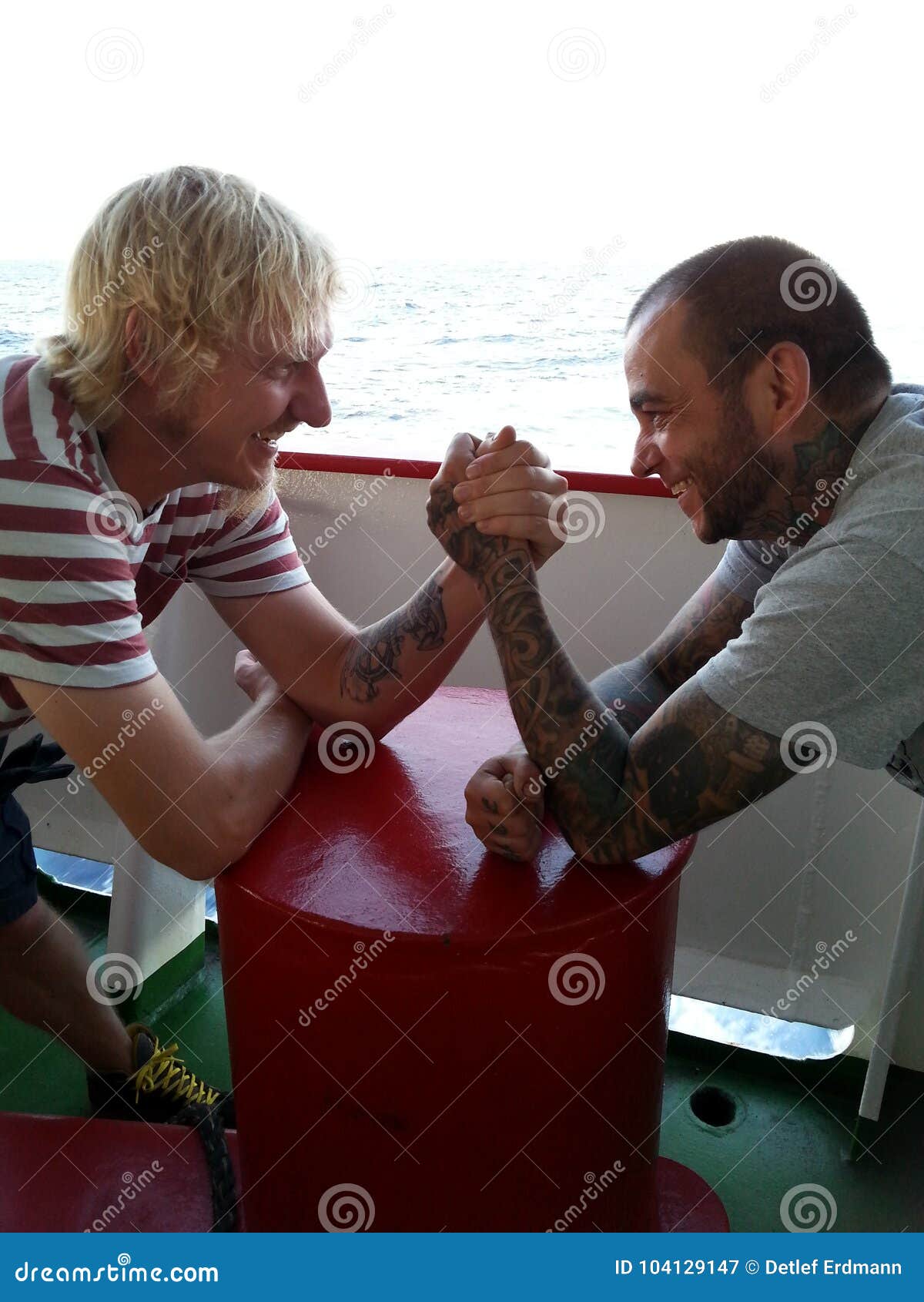two seamen are arm wrestling on board of a vessel at sea
