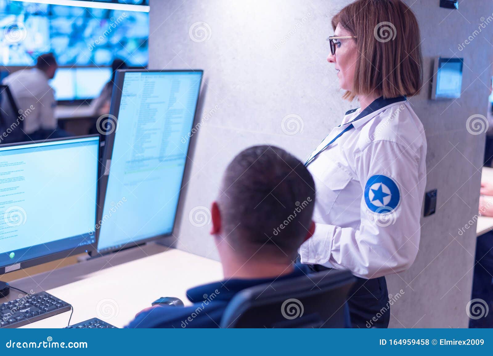Two Security Guards Working on Computers while Sitting in the Main