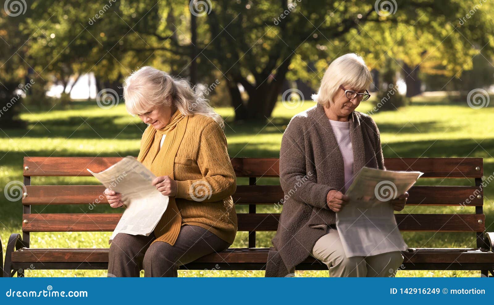 Two Senior Offended Female Friends Reading Newspapers, Sitting on Bench in  Park Stock Image - Image of fight, couple: 142916249