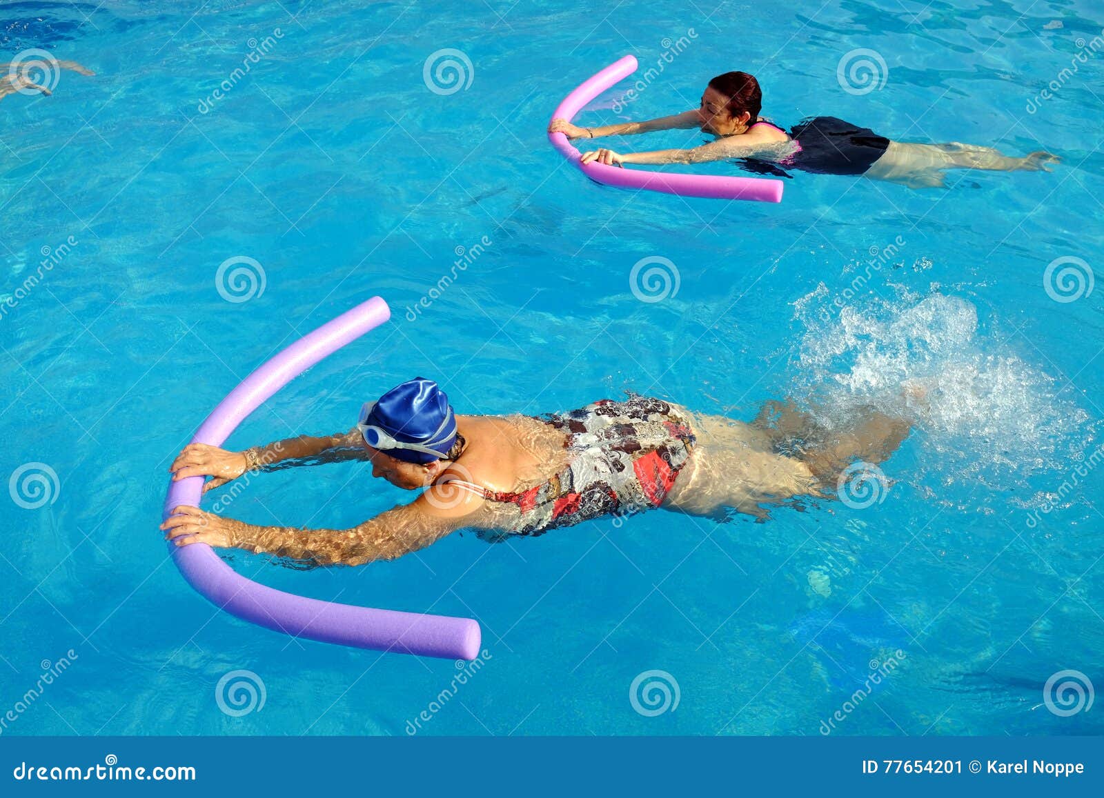 two senior women doing swimming exercise in pool.
