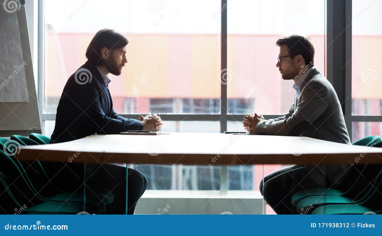 two businessmen sitting opposite at table, confrontation and negotiation