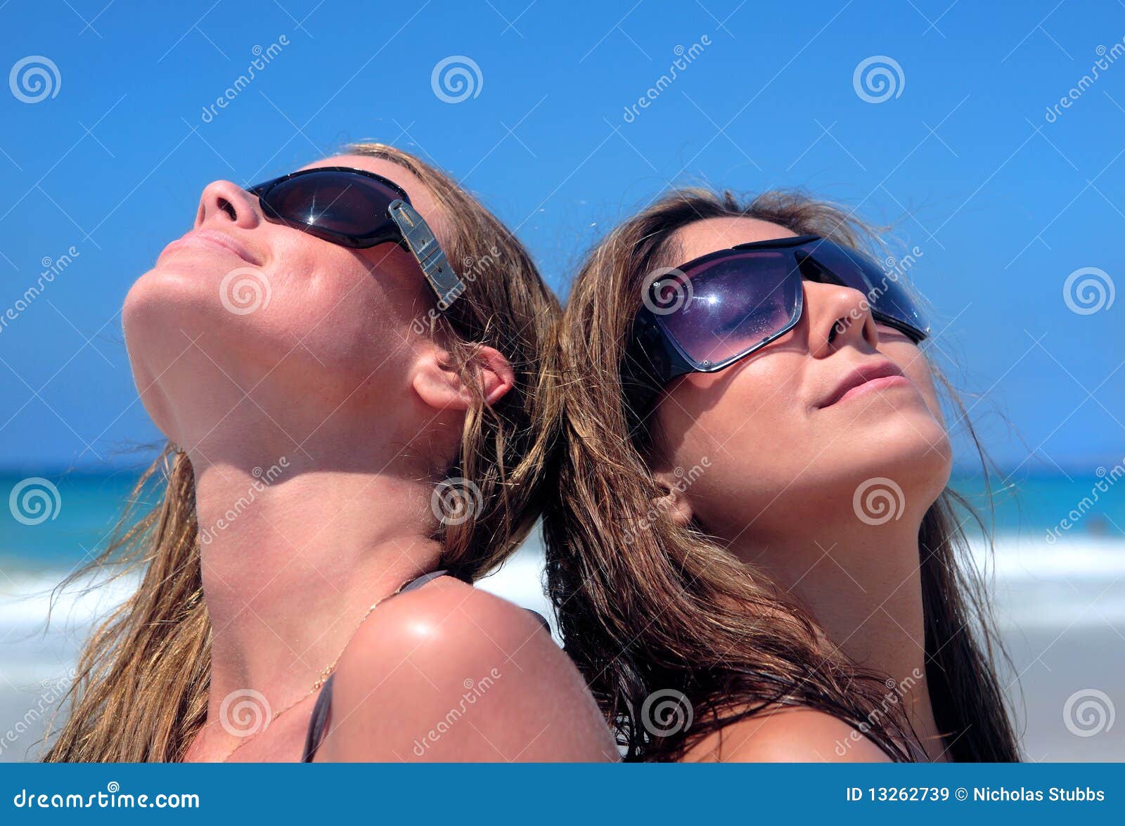 Two Young Women Sunbathing on a Sandy Beach Stock Image