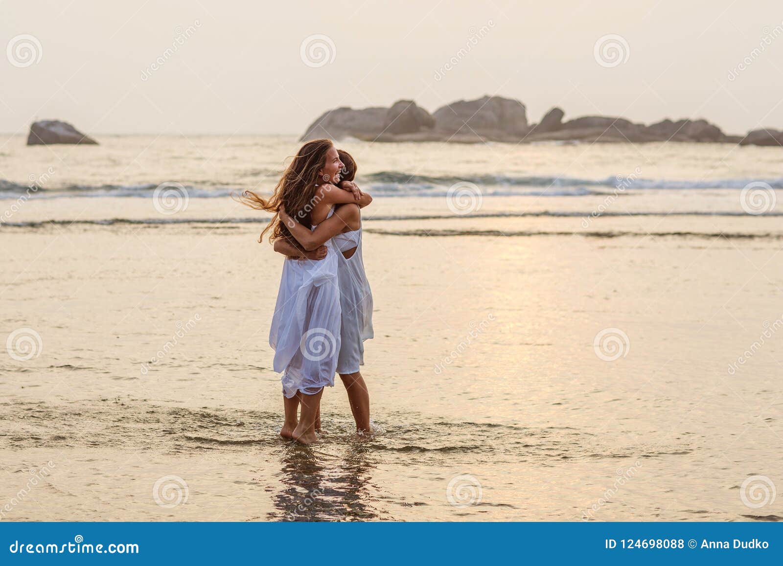 Two Little Naked Sisters Playing On The Beach At Sunset 