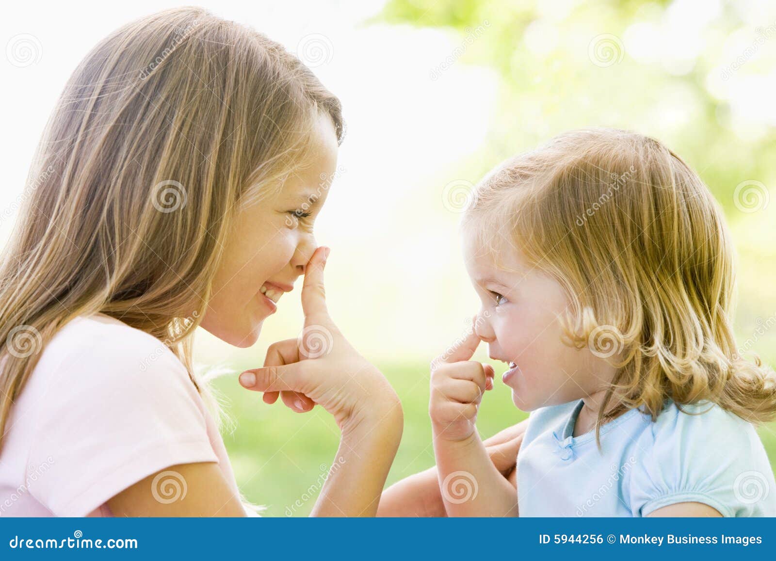 two sisters playing outdoors and smiling