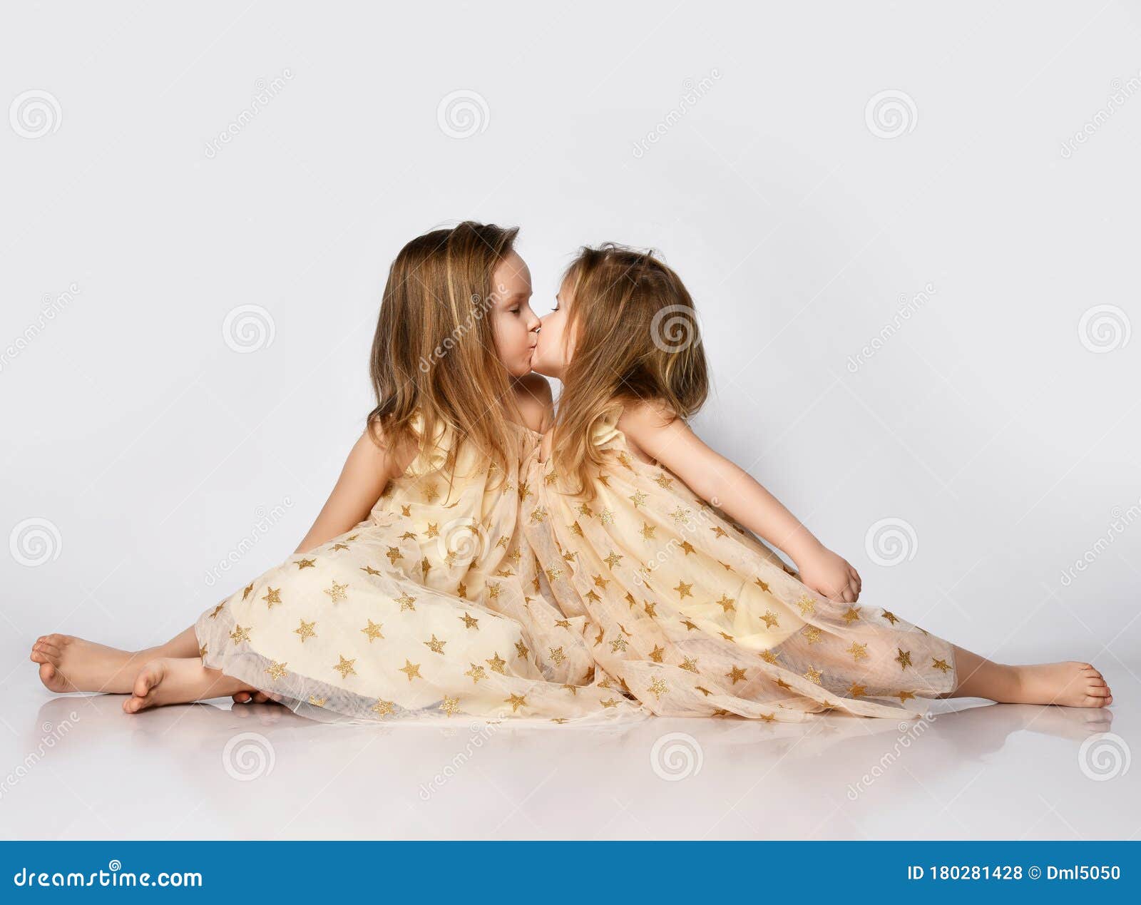 Two Small Beautiful Smiling Girls Sisters In Same Dresses With Stars Barefoot Sitting On Floor 
