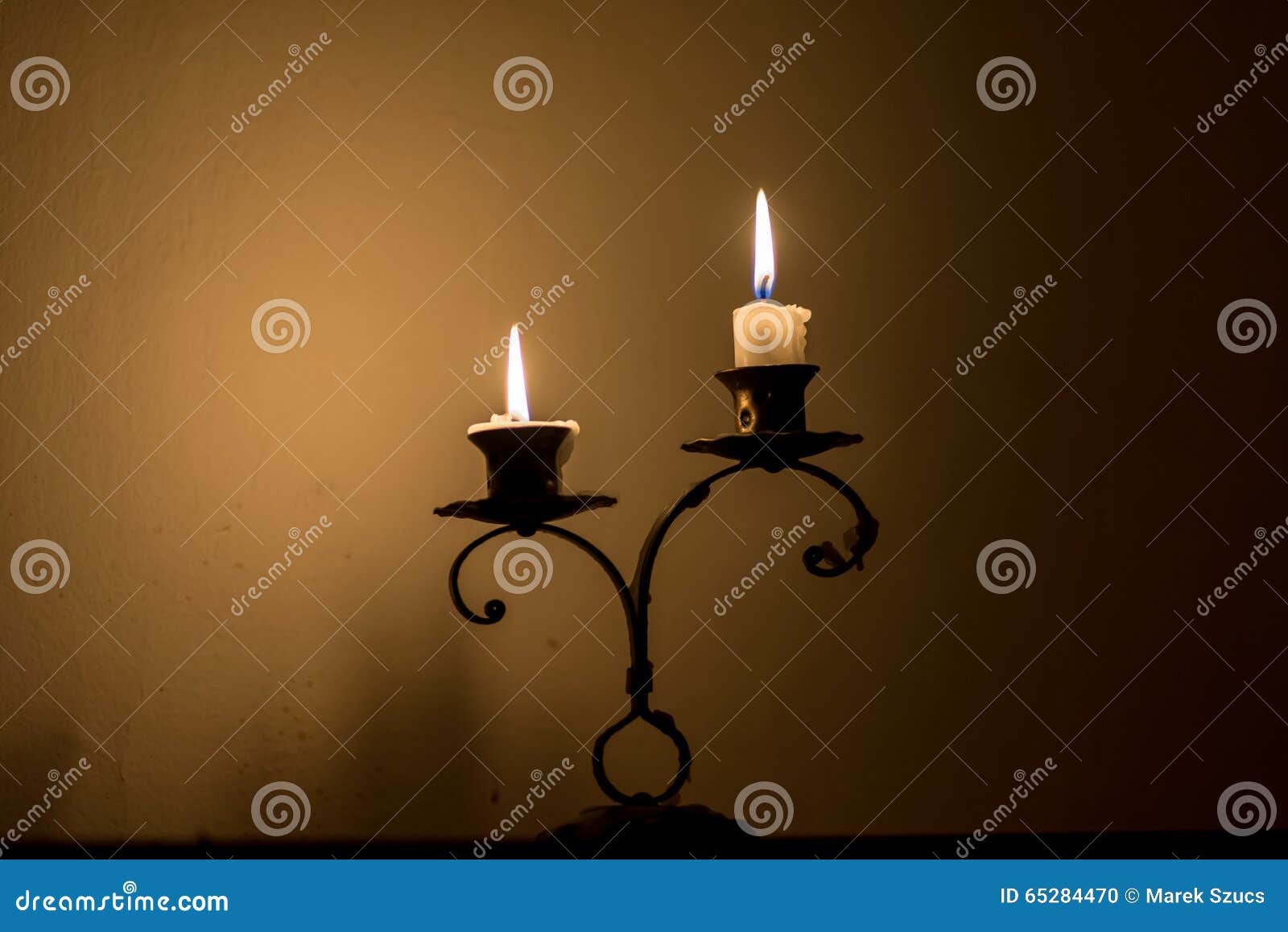 Two Small Candles on Holder Over Melted Wax, in Dark Stock Photo