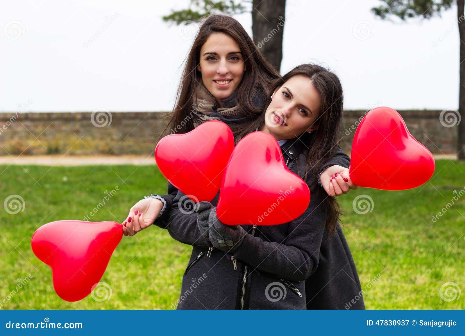 Two smiling girls holding hearts, portrait