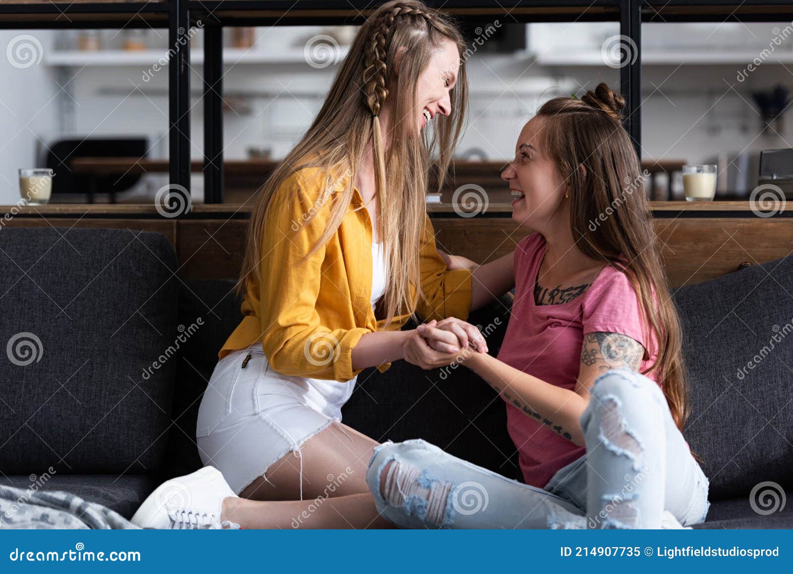 Two Smiling Lesbians Holding Hands While Sitting On Sofa In Living Room Stock Image Image Of