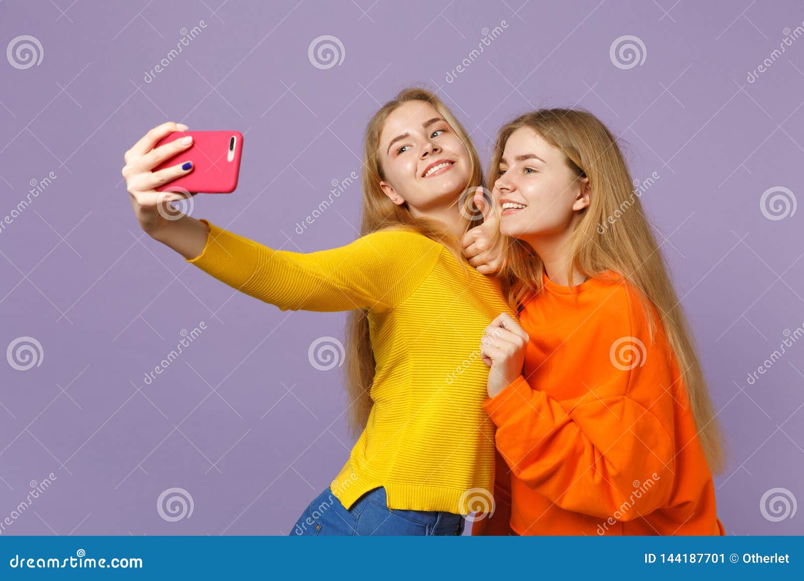 Two Smiling Young Blonde Twins Sisters Girls in Colorful Clothes Doing ...