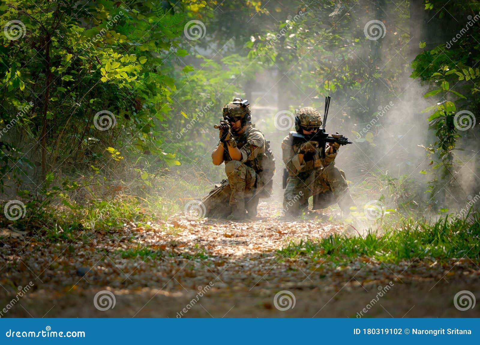two soldiers with the fighting uniform sit on the ground and point gun to target for the concept war battle in jungle
