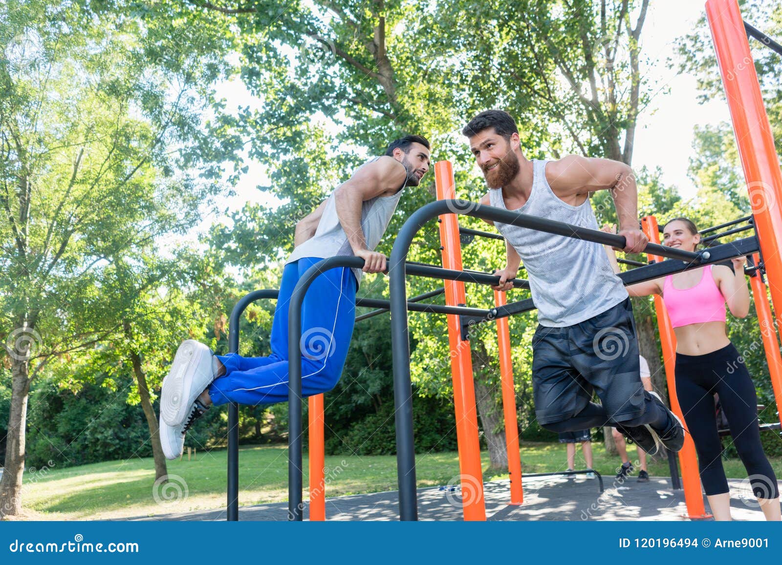 Two Strong Young Men Doing Dips Exercise for the Upper Body Outdoors
